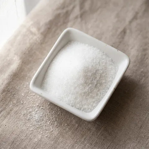 A small white dish of fine sweetener crystals