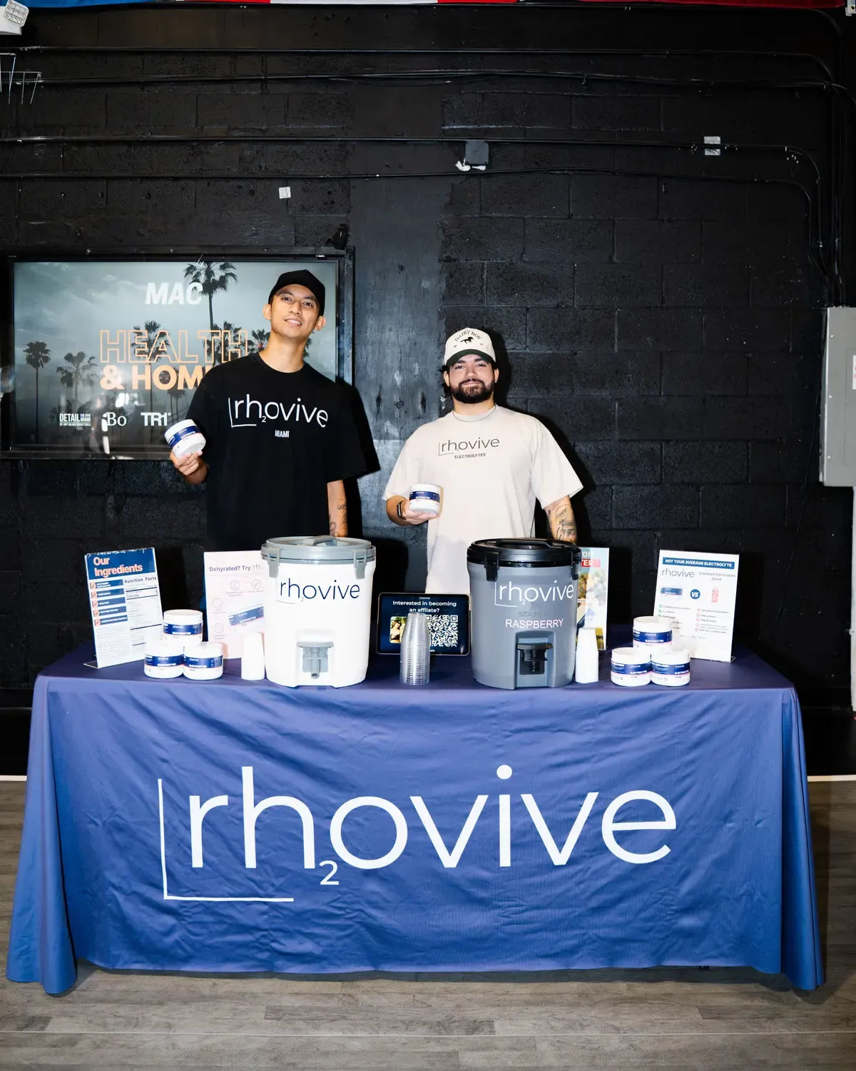 Two Rhovive founders behind the Rhovive sampling table, holding jars