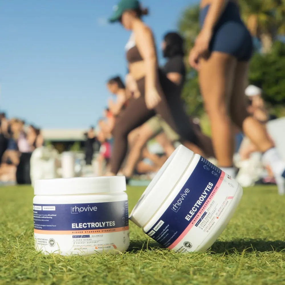 Jars of Rhovive Peach and Raspberry on the grass during an outdoor workout